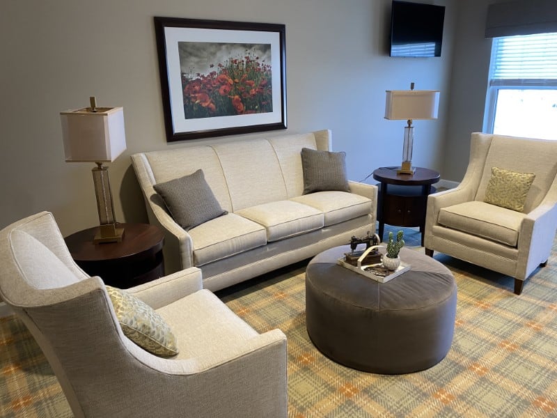 Traditions of Columbus common area with gray furniture and plaid carpet.