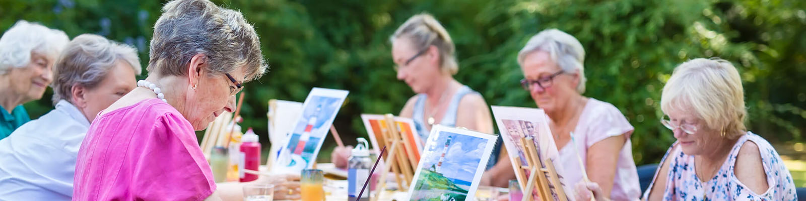 A group of senior women sitting outdoors at a table for a painting event