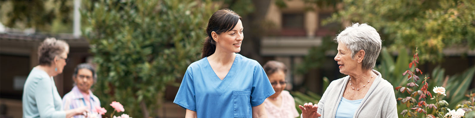 A senior woman walking outdoors with her female nursing assistant