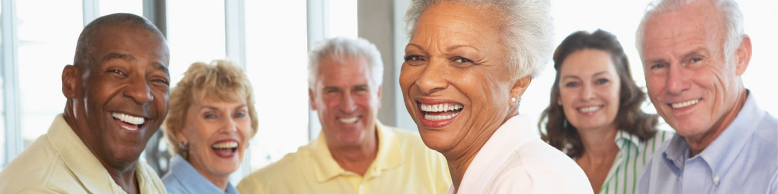 A group of senior men and senior women siting at a table smiling together