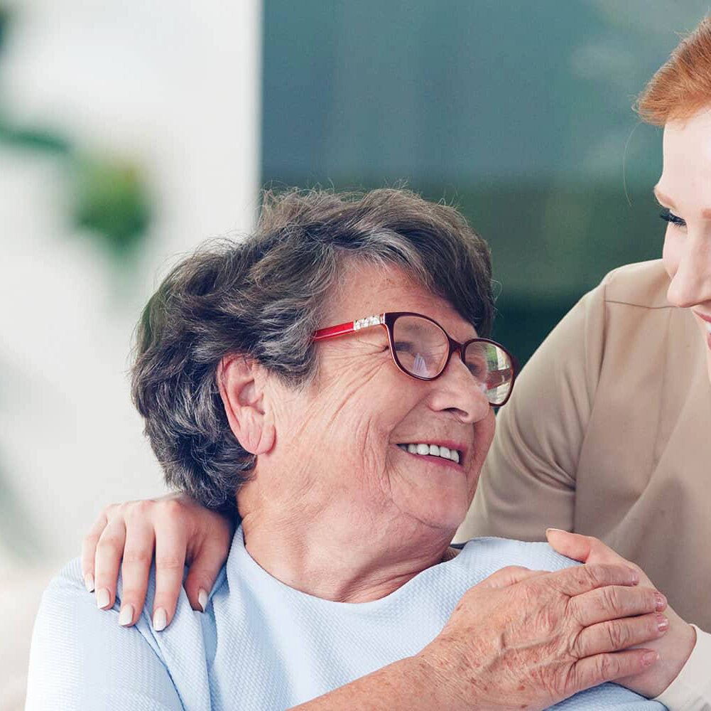 A senior living employee walking with a female resident outdoors