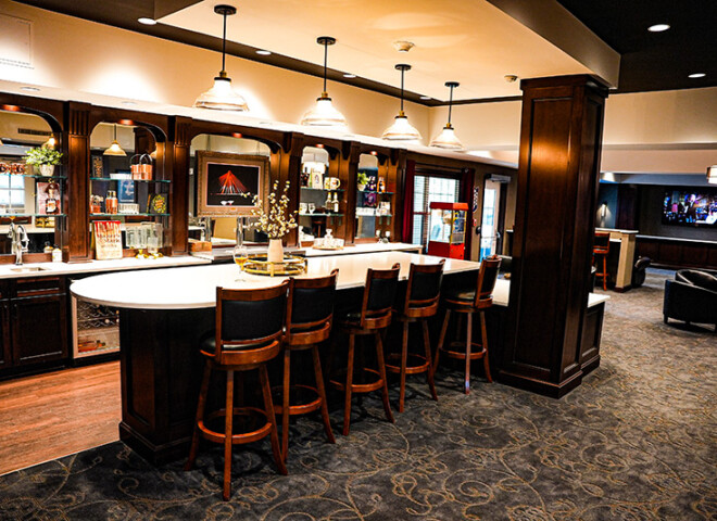 Traditions of Columbus bar with an island, chairs, movie theatre in the background